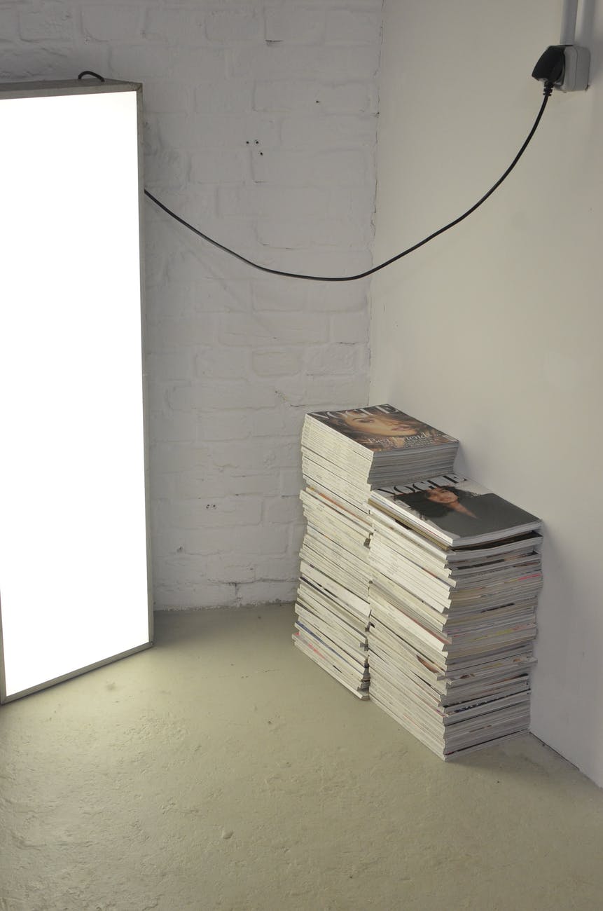 stacked magazines on floor near photo studio lamp